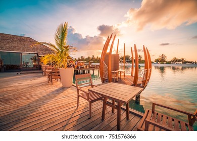 Restaurant at the beach. Sunset colors and wooden table and chair ready for dinner or lunch or breakfast. Luxury beach restaurant