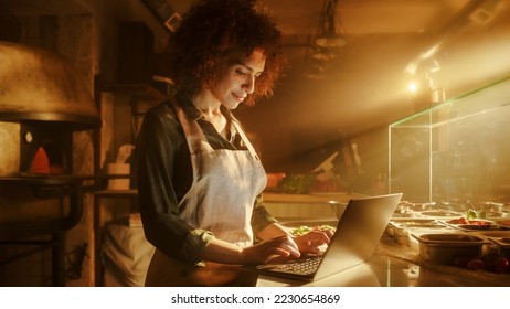In Restaurant: Beautiful Female Chef Using Laptop Computer. Authentic Pizzeria With Delicious Organic Eco Food. Bi-racial Female Entrepreneur Working in Her Small Business Family Shop - Powered by Shutterstock