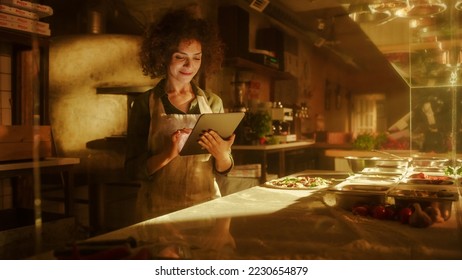 In Restaurant: Beautiful Female Chef Using Laptop Computer. Authentic Pizza Place Cooking Delicious Organic Eco Food. Bi-racial Female Entrepreneur Working on Online Order Small Business Family Shop - Powered by Shutterstock