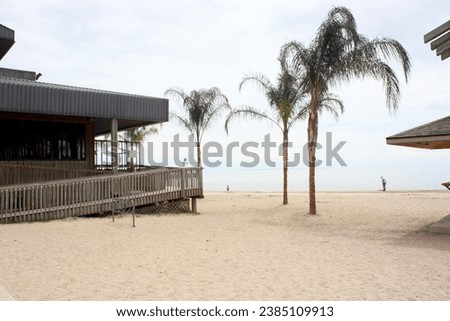 Restaurant building on the beach. Sand sandy. Wood wooden. Ramp. Wheelchair access. Disability-friendly disability friendly business establishment. Palm trees. Water. Lake. Horizon. Accessible. 