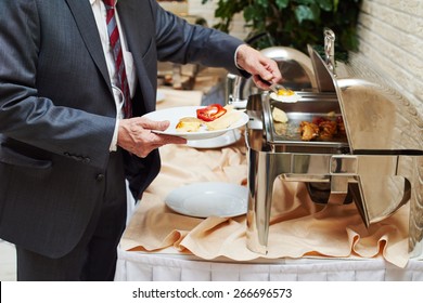 restaurant catering service. Man with food at morning buffet style smorgasbord 