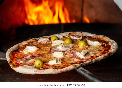 Restaurant chef takes pizza from oven. Preparing traditional italian pizza. chef holding shovel for pizza, Italian pizza is cooked in a wood-fired oven.