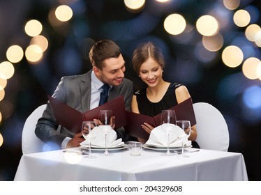 restaurant, couple and holiday concept - smiling couple with menus at restaurant