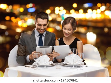 Restaurant, Pärchen, Technik und Urlaubskonzept - Lächelnes Paar mit Menüs auf Tablet PC-Computern im Restaurant