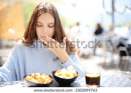 Restaurant customer eating and licking finger in a terrace