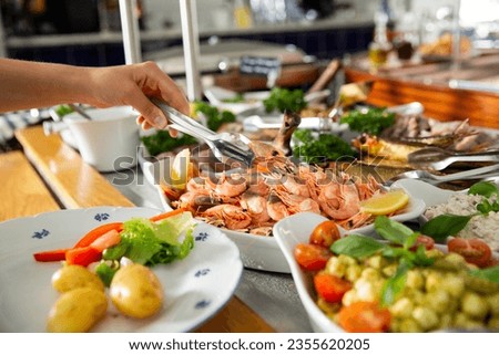 A restaurant customer puts delicious shrimp on a plate. Seafood buffet lunch in a cafe