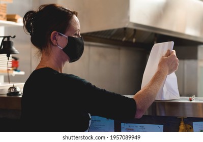 Restaurant Employee Picking Up Take Out Order From A Kitchen Window