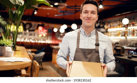 a restaurant employee receives a delivery from a courier. Sending pizza lunch in a package to your home. Work in a small restaurant in the city center. Smiles favorite work - Powered by Shutterstock