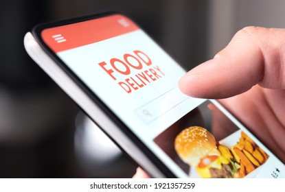 Restaurant Food Delivery Service In Phone. Take Away Menu In Digital Mobile App. Man Ordering Takeout Pizza Or Burger Online. Fast Lunch Delivered Home. Person Using Smartphone And Mockup Application.