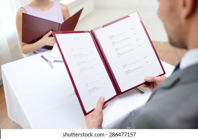 restaurant, food, eating and holiday concept - close up of couple with menu choosing dishes at restaurant - Shutterstock ID 286477157