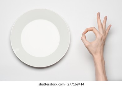 Restaurant And Food Theme: The Human Hand Show Gesture On An Empty White Plate On A White Background In Studio Isolated Top View