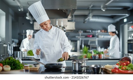 Restaurant Kitchen: Black Female Chef Cooking Delicious and Traditional Authentic Food, Uses Oil on Pan Getting Ready to Fry Organic Free Range Meat Patty. Preparing gourmet Dishes. Wide Shot - Powered by Shutterstock