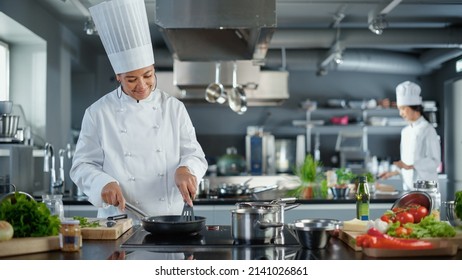 Restaurant Kitchen: Black Female Chef Cooking Delicious and Traditional Authentic Food, Uses Oil on Pan Getting Ready to Fry Organic Free Range Meat Patty. Preparing gourmet Dishes. Wide Shot - Powered by Shutterstock