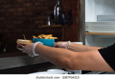 Restaurant Kitchen Employee Placing Food Order On Window For Server To Pick Up