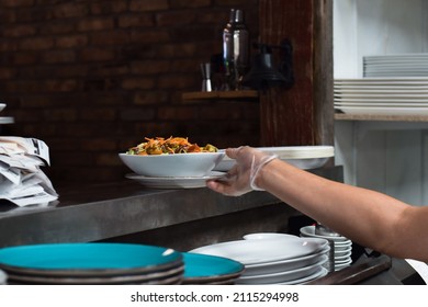 Restaurant Kitchen Employee Placing Salad Bowl On Window For Server To Pick Up