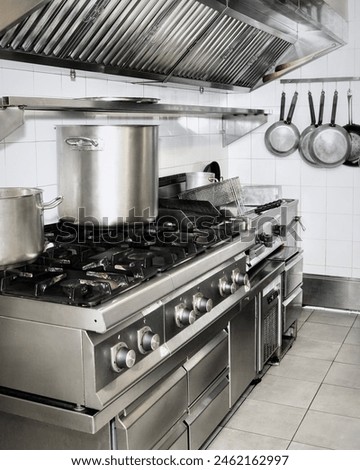 Restaurant kitchen with essential utensils and a pot on the stove. Part of a kitchen in the restaurant or hotel with professional equipments - steel gas cooker, pots and pans.
