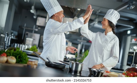 Restaurant Kitchen: Portrait of Asian and Black Female Chefs Preparing Dish, Tasting Food, Doing High-Five in Successful Celebration. Two Professionals Cooking Delicious, Authentic Food, Healthy Meals - Powered by Shutterstock