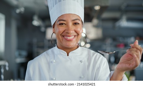 Restaurant Kitchen: Portrait of Black Female Chef Preparing Dish, Tasting Food and Enjoying it. Professional Cooking Delicious, Authentic, traditional Food, using Healthy Ingredients for Meal Recipe - Powered by Shutterstock