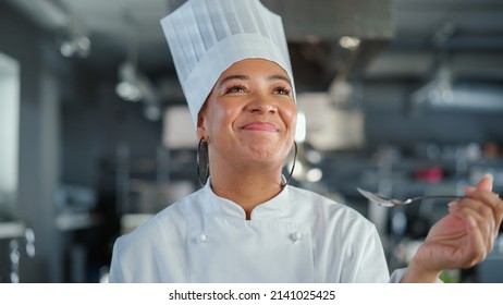 Restaurant Kitchen: Portrait of Black Female Chef Preparing Dish, Tasting Food and Enjoying it. Professional Cooking Delicious, Authentic, traditional Food, using Healthy Ingredients for Meal Recipe - Powered by Shutterstock