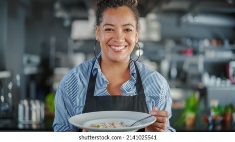 Restaurant Kitchen: Portrait of Black Female Chef Prepares Dish, Tasting Food, Enjoying it. Professional Cook Eats Delicious, Authentic, traditional Food using only Healthy Ingredients for Meal Recipe - Powered by Shutterstock