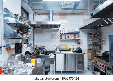 Restaurant Kitchen Without People. There Is No One In Kitchen Of Cafe. Concept - Work In Restaurant Has Been Stopped. Small Restaurant Kitchen With Chrome Equipment. Dishes And Products On Tables.