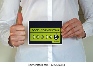 Restaurant Manager Or Other Kitchen Worker With Thumb Up Holds Food Hygiene Rating 5 Sticker From The United Kingdom Food Standards Agency