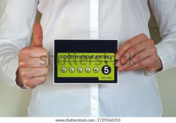 Restaurant manager or other kitchen worker with\
thumb up holds Food Hygiene Rating 5 sticker from The United\
Kingdom Food Standards\
Agency