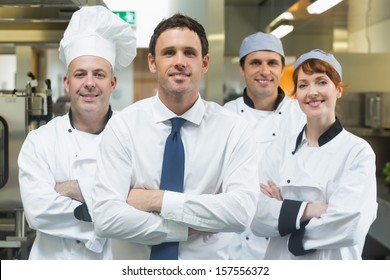 Restaurant manager standing in front of team of chefs smiling at camera