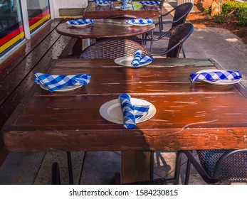 Restaurant Outside Seating With Dinner Plate Setup. Restaurant Outside Seating With Wooden Tables And White Dinner Plates With Blue And White Napkins.