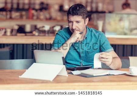 Restaurant owner checking monthly reports on a tablet, bills and expenses of his small business. Start-up entrepreneur concerned about financial reports