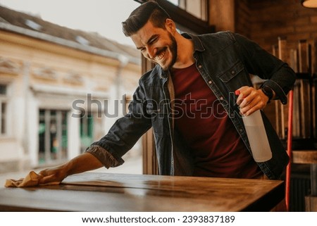 A restaurant owner ensuring tables are squeaky clean with a trusty spray