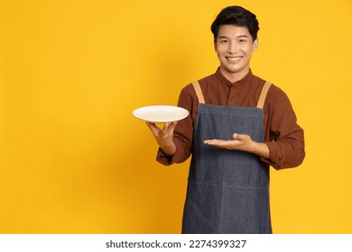 Restaurant owner sme young Asian man holding empty white plate or dish isolated on yellow background - Powered by Shutterstock