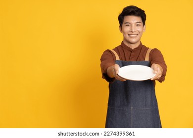 Restaurant owner sme young Asian man holding empty white plate or dish isolated on yellow background - Powered by Shutterstock