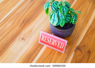 Restaurant Reserved Table Sign With Flowerpot On Wooden Table.