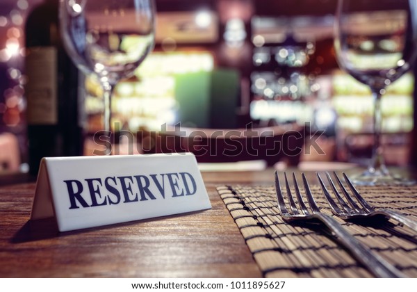 Restaurant reserved table sign with places\
setting and wine glasses ready for a\
party