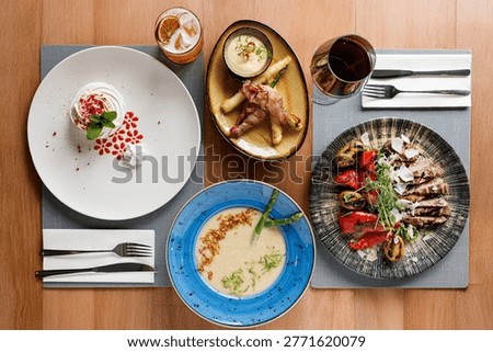 Restaurant table with assorted dishes top view
Fine dining meal set with multiple plates
Overhead view of restaurant food and wine