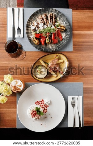 Restaurant table with assorted dishes top view
Fine dining meal set with multiple plates
Overhead view of restaurant food and wine