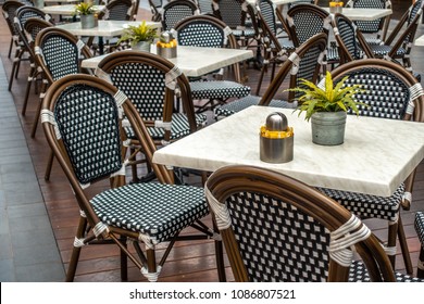 Restaurant table and chairs settings in outdoor dinning area  Elegant chair with stylish marble surface tabletop. Green plants in pot placed on table.