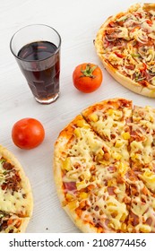 restaurant table served with pizzas of different ingredients, glass with soda and decorated with tomatoes, food and drink in studio, texture of delicious snacks