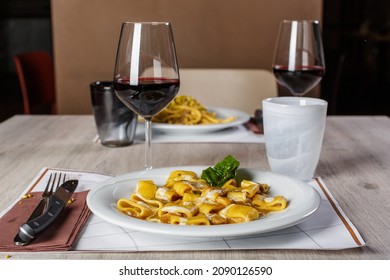 A restaurant table set for two with two first courses and two glasses of red wine
