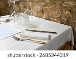Restaurant table setup with white tablecloth and utensils 