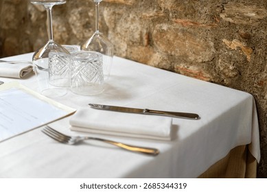 Restaurant table setup with white tablecloth and utensils 