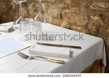 Restaurant table setup with white tablecloth and utensils 