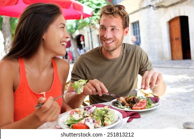 Restaurant tourists couple eating at outdoor cafe. Summer travel people eating healthy food together at lunch during holidays in Mallorca, Spain. Asian Caucasian multiracial young adults.