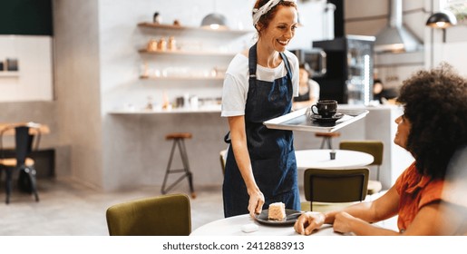 Restaurant waitress smiling and giving her customer a friendly greeting as she brings her food on a tray. Female barista serving a woman a cup of coffee and a piece of cake in a cafe. - Powered by Shutterstock