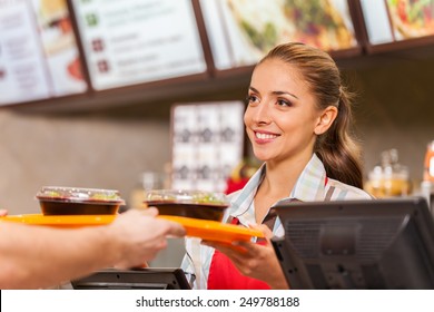 Restaurant-Mitarbeiter serviert zwei Fast-Food-Mahlzeiten mit Lächeln. Frau, die ein Fastfood-Restaurant mit Salaten hält