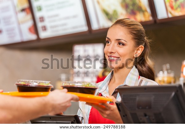 Restaurant worker\
serving two fast food meals with smile. woman holding tray with\
salads at fast food\
restaurant