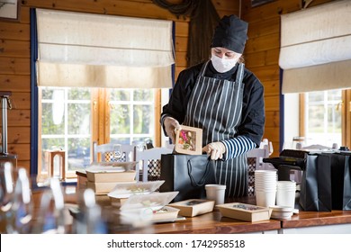 Restaurant Worker Wearing Protective Mask And Gloves Packing Food Boxed Take Away. Food Delivery Services And Online Contactless Food Shopping.
