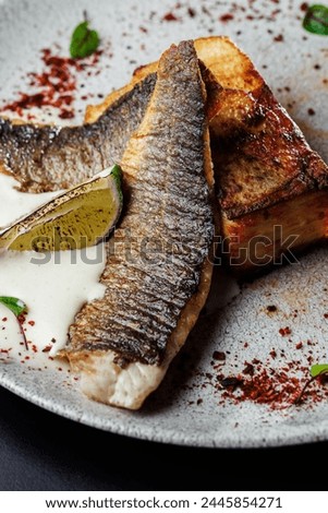 restaurant-style presentation of Seabass with potato gratin and celery sauce, elegantly served on a black table. Perfect choice for culinary promotions and food enthusiasts