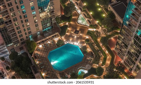 Resting Area Among Skyscrapers With Illuminated Swimming Pool And Sunbed In Dubai Downtown Night Timelapse. Aerial Top View From Above